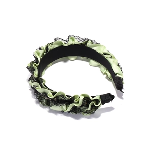 Detail of light green pleated fabric headband with black lace trim and small rhinestones