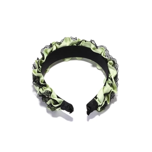 Close-up of pleated light green satin headband with black lace trim and rich textures