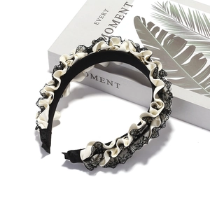 Elegant black lace and cream satin pleated headband displayed on a decorative book box