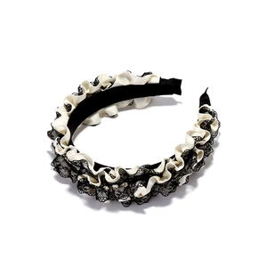 Detailed view of pleated satin headband with black lace trim and sparkling rhinestones