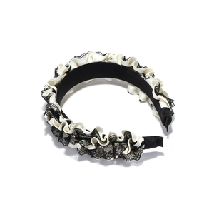Detail of pleated white satin headband with black floral lace layering on a wide base