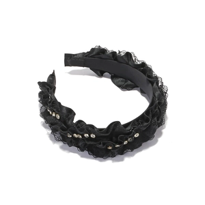 Close-up of black lace headband with elegant rhinestones and ruffled fabric texture