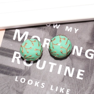 Vintage mint green enamel stud earrings with golden branch textures in a 45-degree view