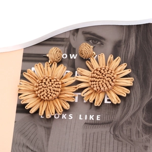 Détails macro des boucles d'oreilles tournesol en raphia avec textures bohèmes