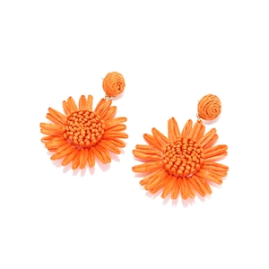Détail de boucles d'oreilles tournesol en raphia orange tissé à la main et textures