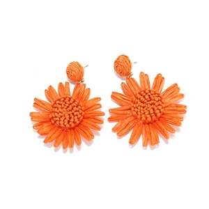 Gros plan détaillé de boucles d'oreilles tournesol en raphia faites main orange vif