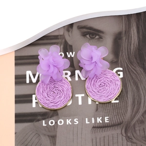 Chic purple resin flower earrings with woven raffle details on a fashion magazine background
