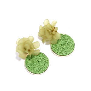 Detail of bohemian earrings with frosted resin flowers and green woven raffia disks