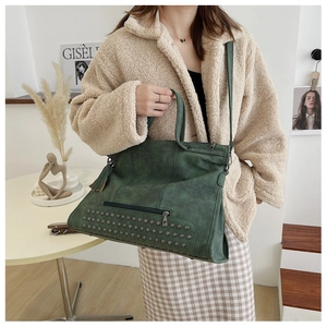 Close-up of vintage dark green rivet tote bag with tassel detail on a fashion model