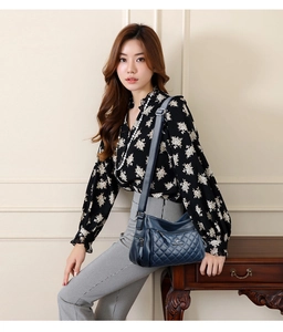 Detail of dark blue quilted crossbody bag with adjustable strap and multi-zipper compartments