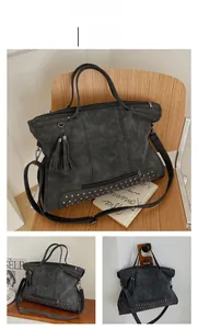 Close-up of black retro tote bag with fringe tassel detail and metallic stud accents
