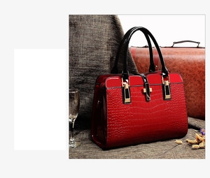 Détail du sac à main rouge à texture crocodile avec fermoir doré sur valise rétro