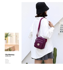 Detail of purple nylon crossbody bag with multiple zippers and adjustable strap