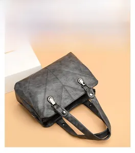 Close-up of gray PU leather handbag featuring geometric stitching and silver hardware