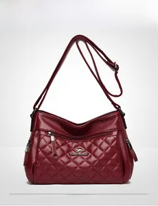 Close-up of burgundy leather crossbody bag with quilted stitching and zip pockets