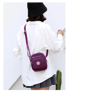Detailed side view of purple nylon crossbody bag with multiple zipper compartments