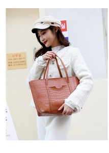 Borsa tote marrone effetto coccodrillo indossata da una modella in giacca tweed