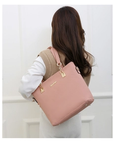 Pink tote bag on model showing size and matte leather texture with gold logo detail