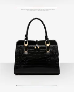Détail d'un sac à main noir en cuir verni façon crocodile avec fermoir doré poli