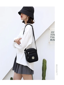 Fashionable black nylon crossbody bag with multi-layer zippers worn by a female model
