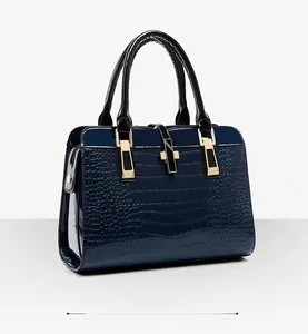 Détail d'un sac à main bleu foncé gaufré crocodile avec finition brillante et fermoir doré