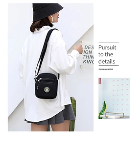 Detail view of black nylon crossbody bag with dual-zipper main compartments and logo
