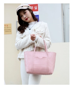 Borsa tote rosa con trama a coccodrillo e tasca a onda indossata da modella elegante