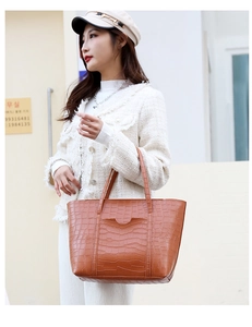 Detail of a brown crocodile pattern tote bag with wavy front pocket on a model