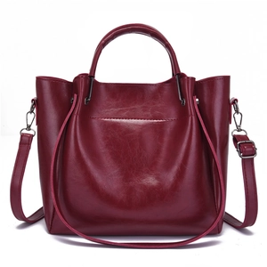 Deep red wine faux leather handbag with adjustable shoulder strap on white background