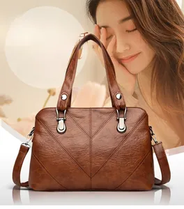 Close-up of brown lychee-textured leather bag with V-shaped stitching and silver hardware