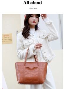 Detail of a brown crocodile pattern tote bag featuring a decorative semi-circular front pocket