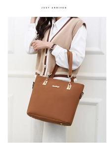 Detail of brown faux leather tote bag with gold chain accents and metallic logo