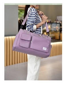 Detail of purple waterproof travel bag with large capacity, logo and adjustable shoulder strap