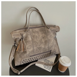 Detail of vintage gray tote bag with metal studs, tassels, and adjustable shoulder strap