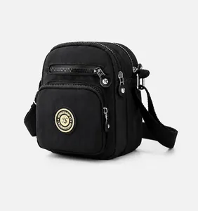 Detail view of black oxford nylon crossbody bag with multiple zip pockets and adjustable strap