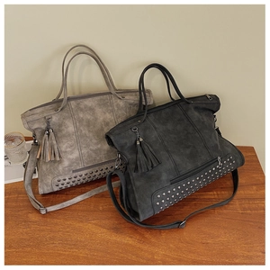 Detail of vintage tote bags with metal rivets and fringe tassels on retro matte leather