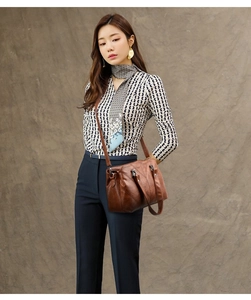 Detail of brown faux leather handbag with V-shaped stitching and dual top handles