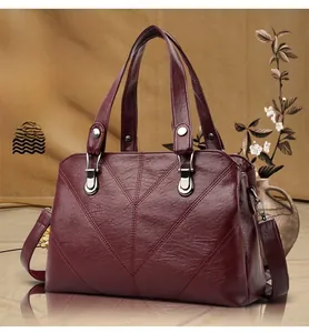 Close-up of burgundy textured leather tote bag with V-shaped stitching and silver hardware