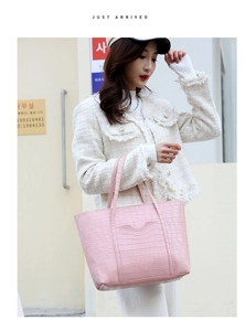 Outdoor street shot of a large pink tote bag featuring elegant crocodile skin texture
