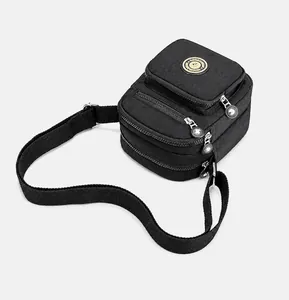 Detailed overhead view of black nylon crossbody bag with three zipper compartments