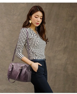 Detail of purple tote bag with geometric stitching shown on shoulder for size context