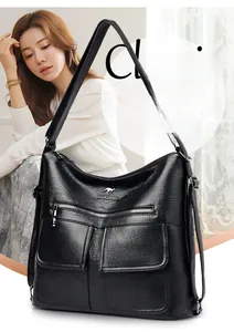 Detalle de bolso negro de piel con textura de lichi y bolsillos frontales con logotipo