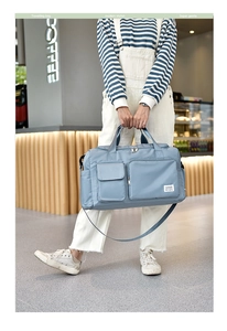 Blue large capacity travel bag held by model in a cafe, showing size and waterproof fabric