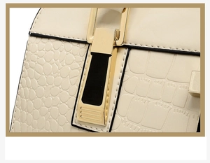 Détail du sac en cuir gaufré crocodile avec fermoir en métal doré et bords noirs huilés