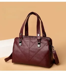 Close-up of wine red faux leather bag featuring V-shaped stitching and metallic hardware