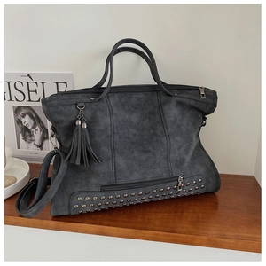 Detail view of large dark grey retro bag featuring metal studs and leather tassels