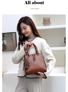 Détail d'un sac à main marron en cuir PU matelassé avec pompon et pendentif chat sur blanc