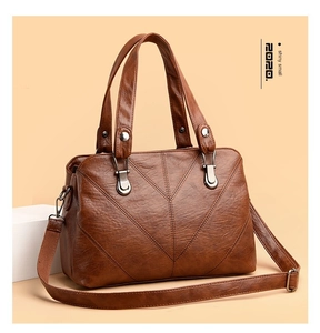 Close-up of brown faux leather handbag showing V-shaped geometric stitching and hardware
