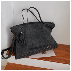 Macro shot of dark grey vintage tote bag featuring metallic rivets and tassel details