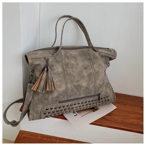 Detail showing vintage grey faux leather texture with twin tassels and metal rivet accents
